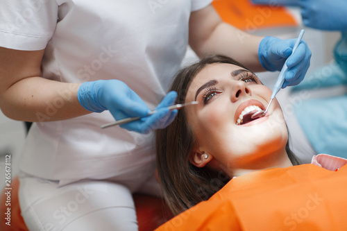 Obraz Dibond Klinika dentystyczna. Odbiór, badanie pacjenta. Pielęgnacja zębów Młoda kobieta przechodzi badanie dentystyczne przez dentystę. Koncepcja szczęśliwego pacjenta i dentysty. Dentysta kobiety w gabinecie stomatologicznym rozmawia z