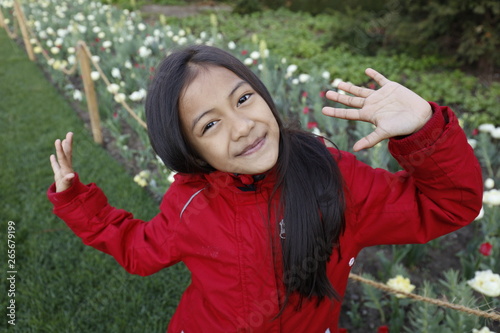 Cuadros en Lienzo Jeune fille asiatique pose en gros plan devant des fleurs avec une veste d'hiver