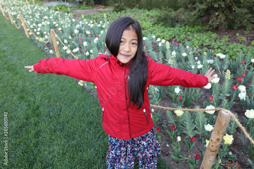 Fotografía Jeune fille asiatique pose devant des fleurs avec une veste d'hiver rouge