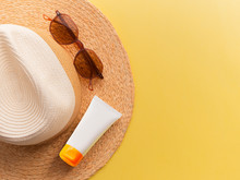 Sunprotection Objects. Straw Woman's Hat With Sun Glasses And Protection Cream Top View Bright Yellow Background Flat. Beach Accessories. Summer Travel Vacation Concept. Sale Kit. Copy Space