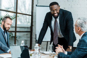 Wall Mural - selective focus of cheerful african american business coach smiling near coworkers