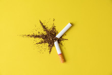 Close Up Cigarette Broken Tobacco Blast Spread On Yellow Pastel Background With Light Side And Little Shadow. No And Quitting Smoking Concept.
