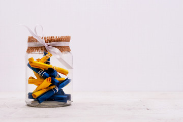 A glass jar with colored notes of craft paper. Light background.