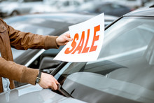 Salesperson Putting Sale Plate On The Car Windshield On The Open Ground Of A Dealership, Close-up View