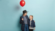 Old grandmother and small child have nice conversation, hold red air balloon, express love to each other, isolated over blue background. Granddaughter celebrates birthday with caring granny.