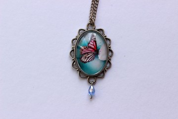 Wall Mural - metal pendant with a butterfly under the glass on white background