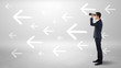 © ra2 studio - Young businessman standing and looking through binoculars with drawn arrows around