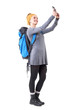 © sharplaninac - Relaxed happy traveling young woman with rucksack taking selfie with smartphone. Full body isolated on white background.