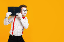 Portrait Of Mime Man Artist Reading Book Isolated On Yellow Background. Copy Space For Text