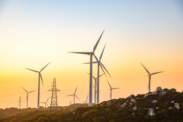 Wind turbines on the mountains are on the beach at sunrise and sunset.