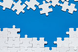 Fototapeta  - White jigsaw puzzle. White puzzle pieces on color background. Unfinished white jigsaw puzzle pieces on color background.
