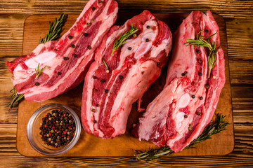 Raw pork ribs with spices and rosemary on a cutting board. Top view