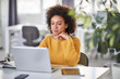 © nenadaksic - Serious mixed race businesswoman dressed casual sitting in modern office and using laptop.