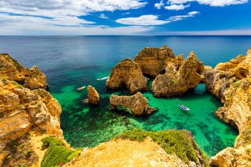 Wall Mural - Panoramic view, Ponta da Piedade near Lagos in Algarve, Portugal. Cliff rocks and tourist boat on sea at Ponta da Piedade, Algarve region, Portugal. Ponta da Piedade, Algarve region, Portugal.