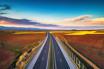 Wall Mural - Aerial view of highway on sunset. Transportation background. Landscape with road near countryside fields