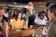 © Monkey Business - Waitress Serving Group Of Young Friends Meeting For Drinks And Food In Restaurant