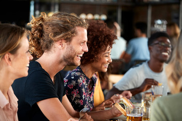 Wall Mural - Group Of Young Friends Meeting For Drinks And Food In Restaurant