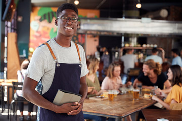 Wall Mural - Portrait Of Waiter Serving In Busy Bar Restaurant