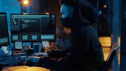 Poster - cybercrime, hacking and technology concept - asian male hacker in mask writing code or using computer virus program for cyber attack in dark room at night