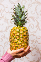 Wall Mural - A woman in the room holds a ripe tasty pineapple in her hands_