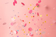 Colorful confetti on pastel pink background. Bright and festive holiday background.