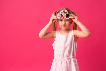 Wall Mural - happy baby girl smiling in sunglasses on pink background. the concept of childhood