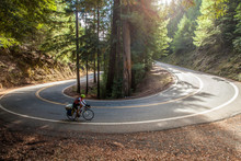 Women Climbing Hairpin Turn Mountain Road On Cross Country Bike. 