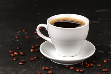 Black coffee, americano, espresso in a white mug with a saucer on a black background, coffee beans are scattered around