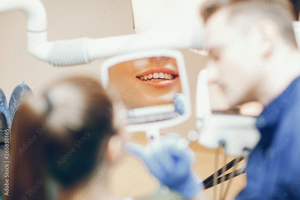 A young and beautiful girl treats her teeth with a dentist - obrazy, fototapety, plakaty 