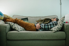 Tabby Cat Sleeps On The Chest Of A Man Asleep On Couch