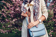 Young woman holding stylish handbag and wearing trendy outfit. Spring female clothes and accessories. Fashion