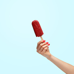 Female hand holding popsicles on a blue background.