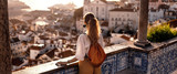 Fototapeta Psy - Female tourist looking at old town from balcony