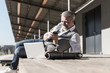 © Westend61 - Smiling mature businessman using laptop outdoors