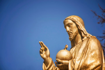 Wall Mural - Gold statue Jesus Christ. He holds the sphere with a cross as a symbol of the trusteeship of Christianity above the earth (faith concept)