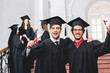 © LIGHTFIELD STUDIOS - selective focus of cheerful men in graduation caps holding diplomas near students