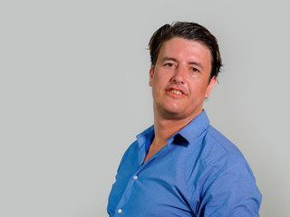 corporate portrait of young attractive and confident entrepreneur man in casual shirt smiling happy and positive looking at the camera in business success