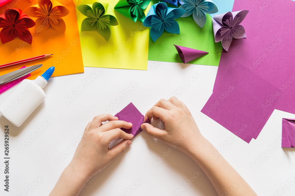 Hands of the girl origami puts flowers from paper of Violet trend color ...