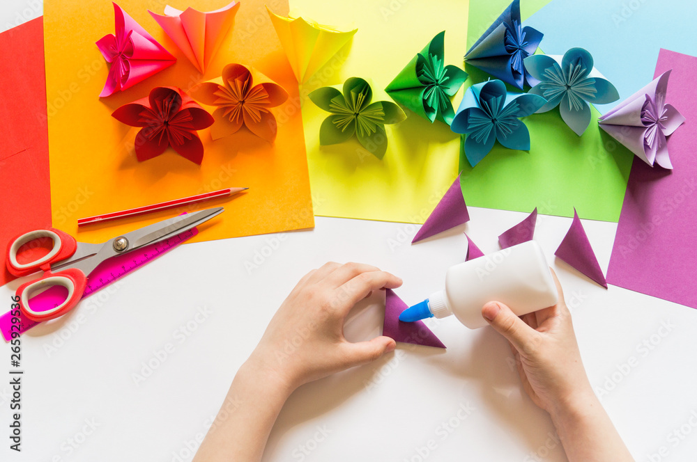 Hands of the girl origami puts flowers from paper of Violet trend color ...