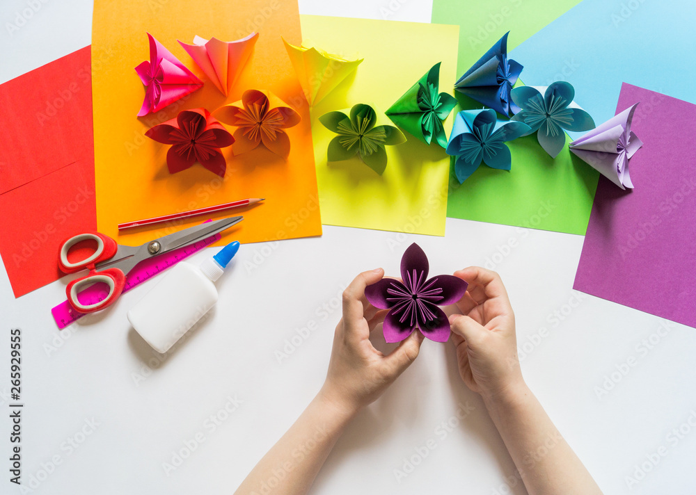 Hands of the girl origami puts flowers from paper of Violet trend color ...