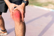Injury from workout concept : The man use hands hold on his knee while running on road in the park. Shot in morning time