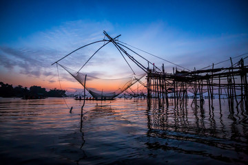  Silhouette of Yokyor, the old traditional equipment asia fishing net of Thai people in Pak Pra Village with sunrise in Phatthalung, Thailand.