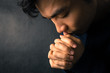 © christianchan - Praying Man Against Dark Background With Copy Space