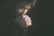 © christianchan - Praying Man Against Dark Background With Copy Space