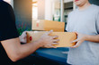 © wutzkoh - Close up of hands cargo staff are delivering cardboard boxes with parcels inside to the recipient's hand.