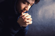 © christianchan - Praying Man Against Dark Background With Copy Space