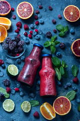 Wall Mural - Red smoothie in bottles with berries and citrus fruits, healthy vitamin drink