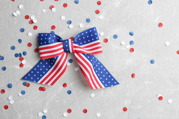 Ribbon bow with American flag pattern and confetti on light background, flat lay with space for text. USA Independence Day