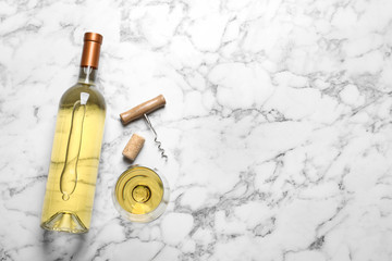 Glass and bottle with white wine on marble background, flat lay. Space for text