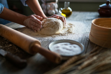 Female hands making dough for pizza. Fresh raw dough. Toned image. Selective focus.